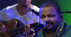 Imagem capa do álbum Sambista Perfeito de Arlindo Cruz. Na imagem temos o cantor segurando instrumento de corda e atrás dele o Morro do Pão de Açúcar, Monumento Natural localizado no bairro da Urca, na cidade do Rio de Janeiro, no Brasil. 